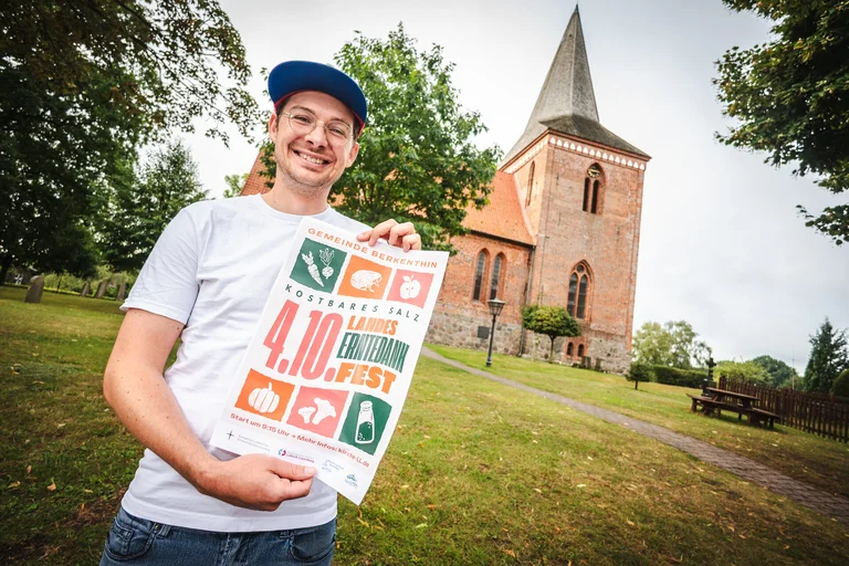 Ein Mann steht mit einem Plakat vor einer Kirche 